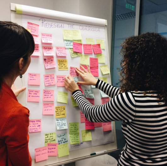 two woman working on a whiteboard 