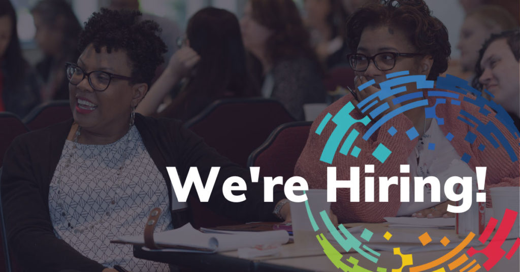 Dark background with two people (one smiling) with glasses looking to the site during an EiC conference. EiC Logo and white text that says We're Hiring!